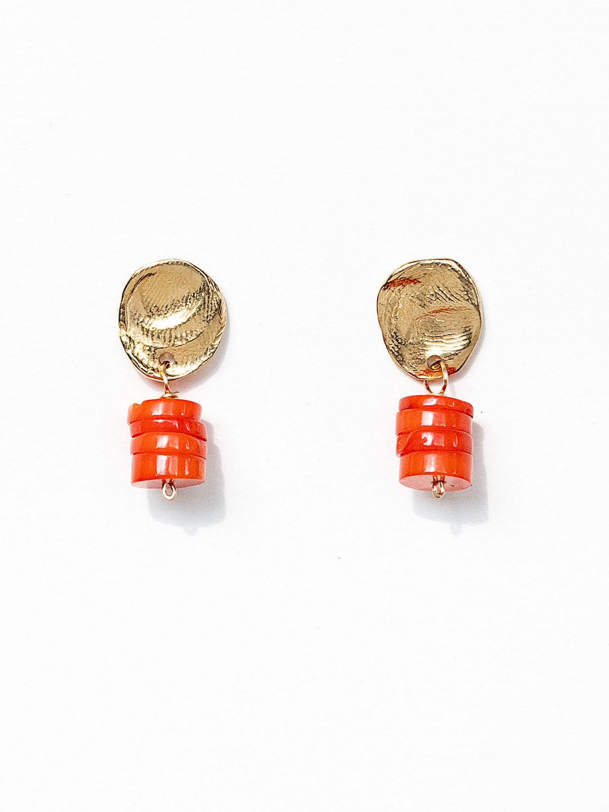 A pair of brass and orange red coral drop earrings by Canadian jewelry designer Michelle Ross. Each earring features a textured gold oval top and a stacked orange cylindrical bead drop.