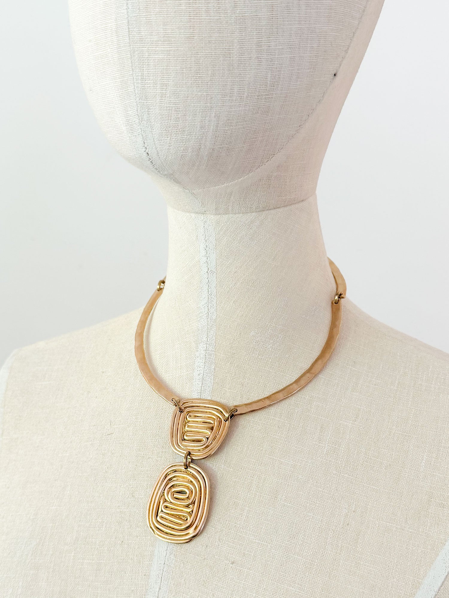 A solid brass collar necklace with a layered circular spiral pendants by Canadian jewelry designer Michelle Ross