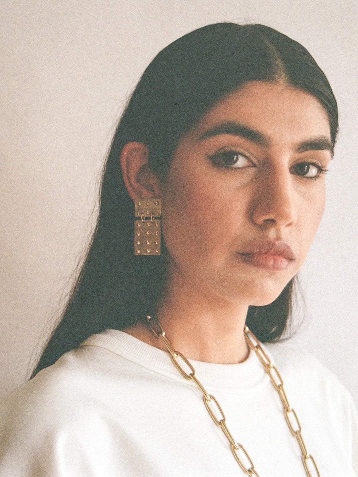 woman wears Lago Lightweight Rectangular Brass Statement Earrings by Michelle Ross