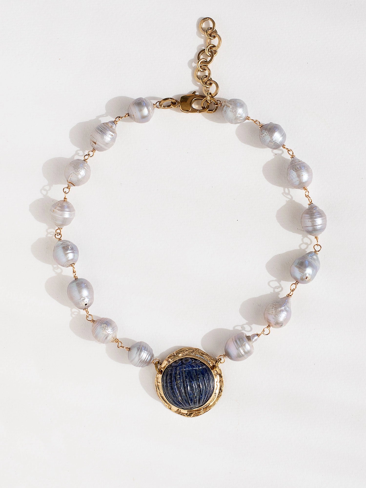 A silver pearl beaded choker necklace with a large statement circular lapis lazuli and brass pendant by Canadian jewellery designer Michelle Ross