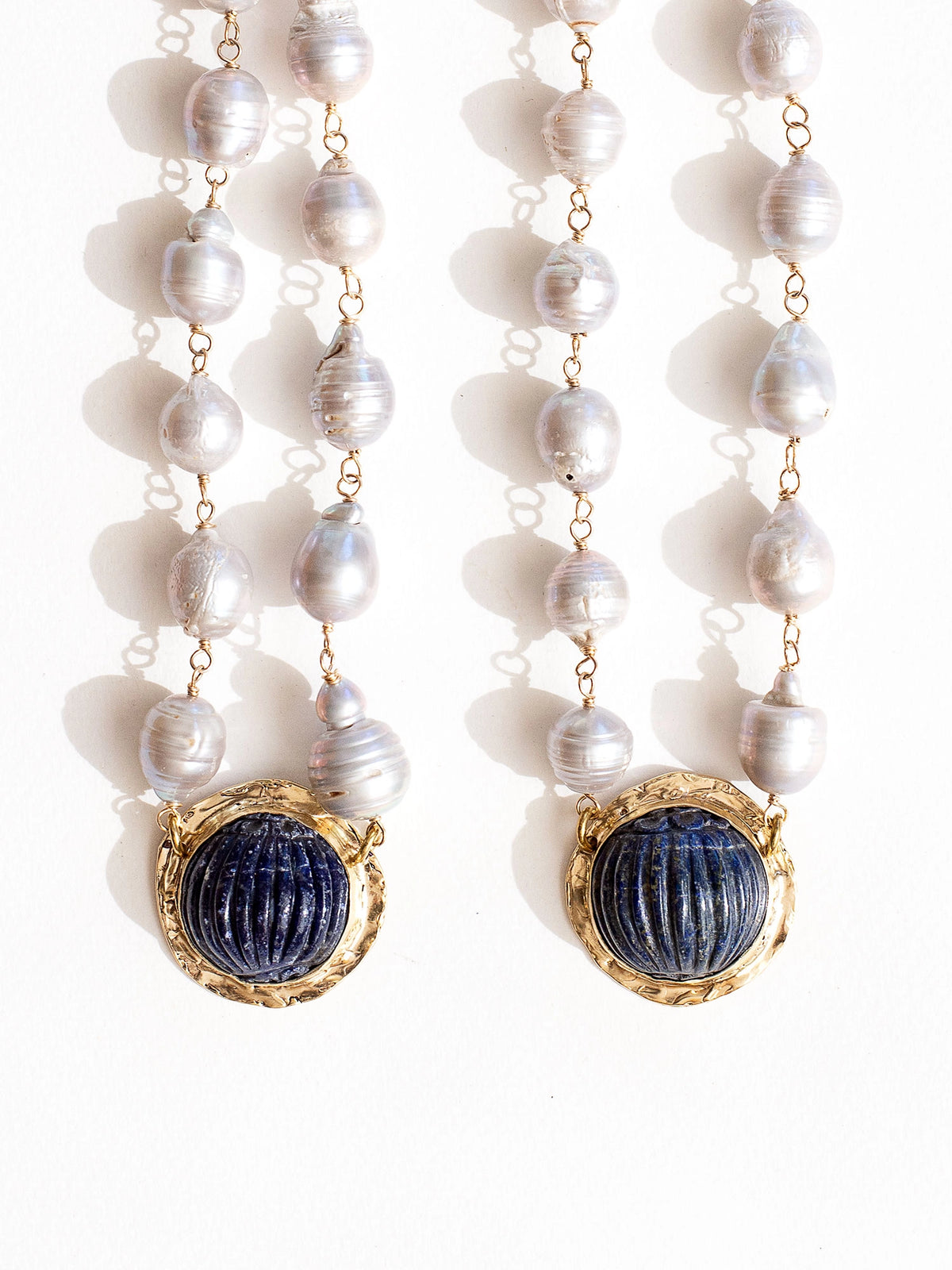 Two silver pearl beaded choker necklaces with a large statement circular lapis lazuli and brass pendant by Canadian jewellery designer Michelle Ross