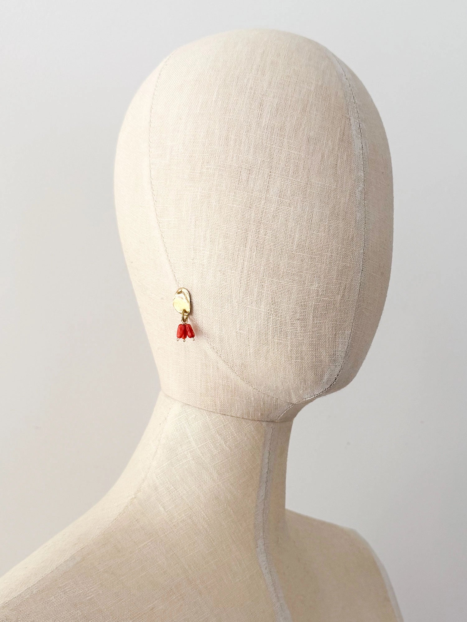 A pair of brass dangle earrings with oval coral orange bead drops by Canadian jewelry designer Michelle Ross