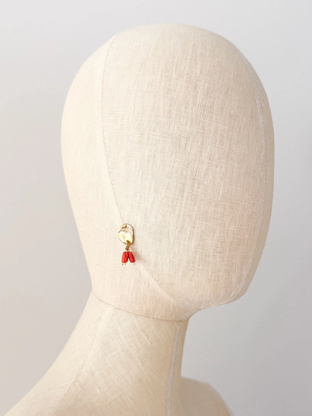 A pair of brass dangle earrings with oval coral orange bead drops by Canadian jewelry designer Michelle Ross