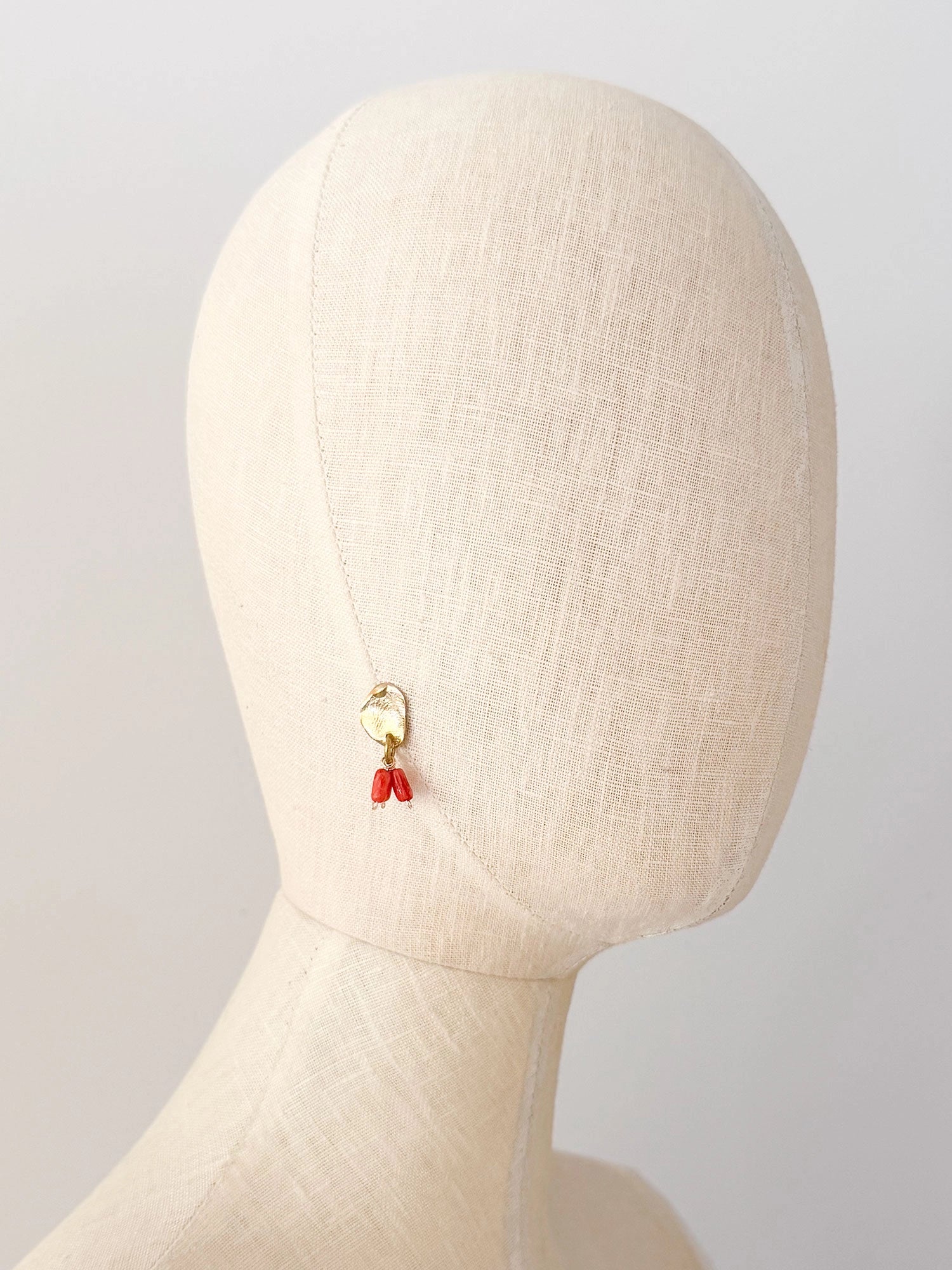 A pair of brass dangle earrings with oval coral orange bead drops by Canadian jewelry designer Michelle Ross