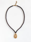 Necklace with small garnet beads and a large horn pendant with brass details by Michelle Ross