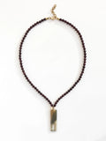 Necklace with small garnet beads and a large horn pendant with brass details by Michelle Ross