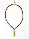Necklace with small garnet beads and a large horn pendant with brass details by Michelle Ross