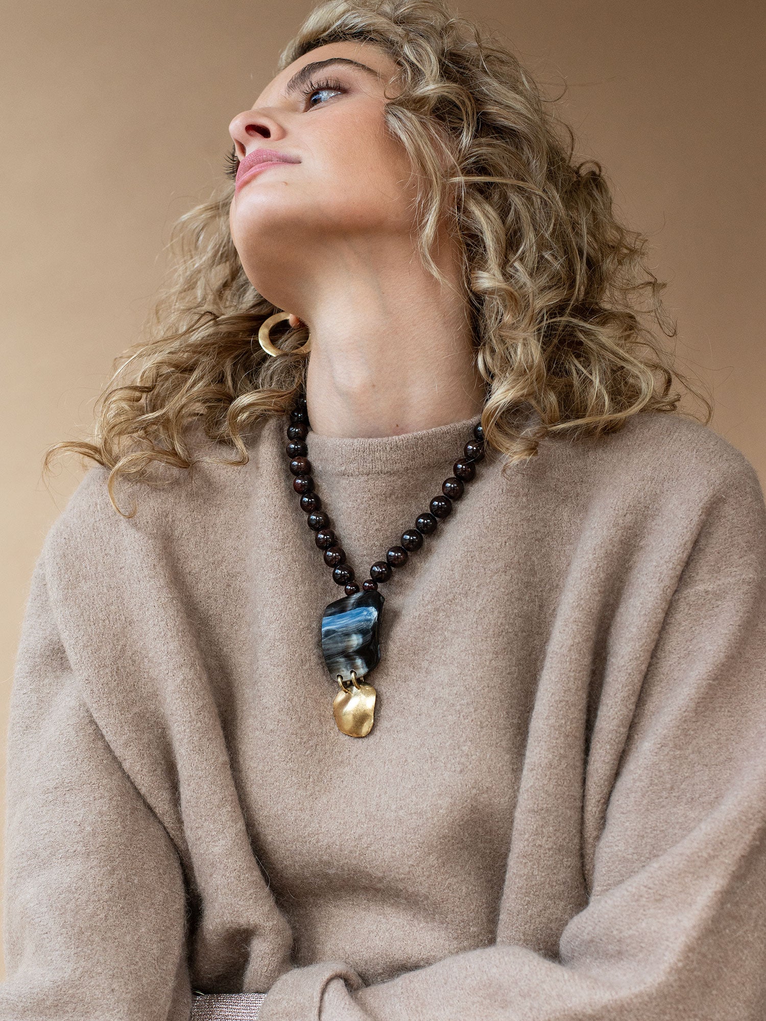 Necklace with garnet beads and a large black horn and brass pendant by Michelle Ross