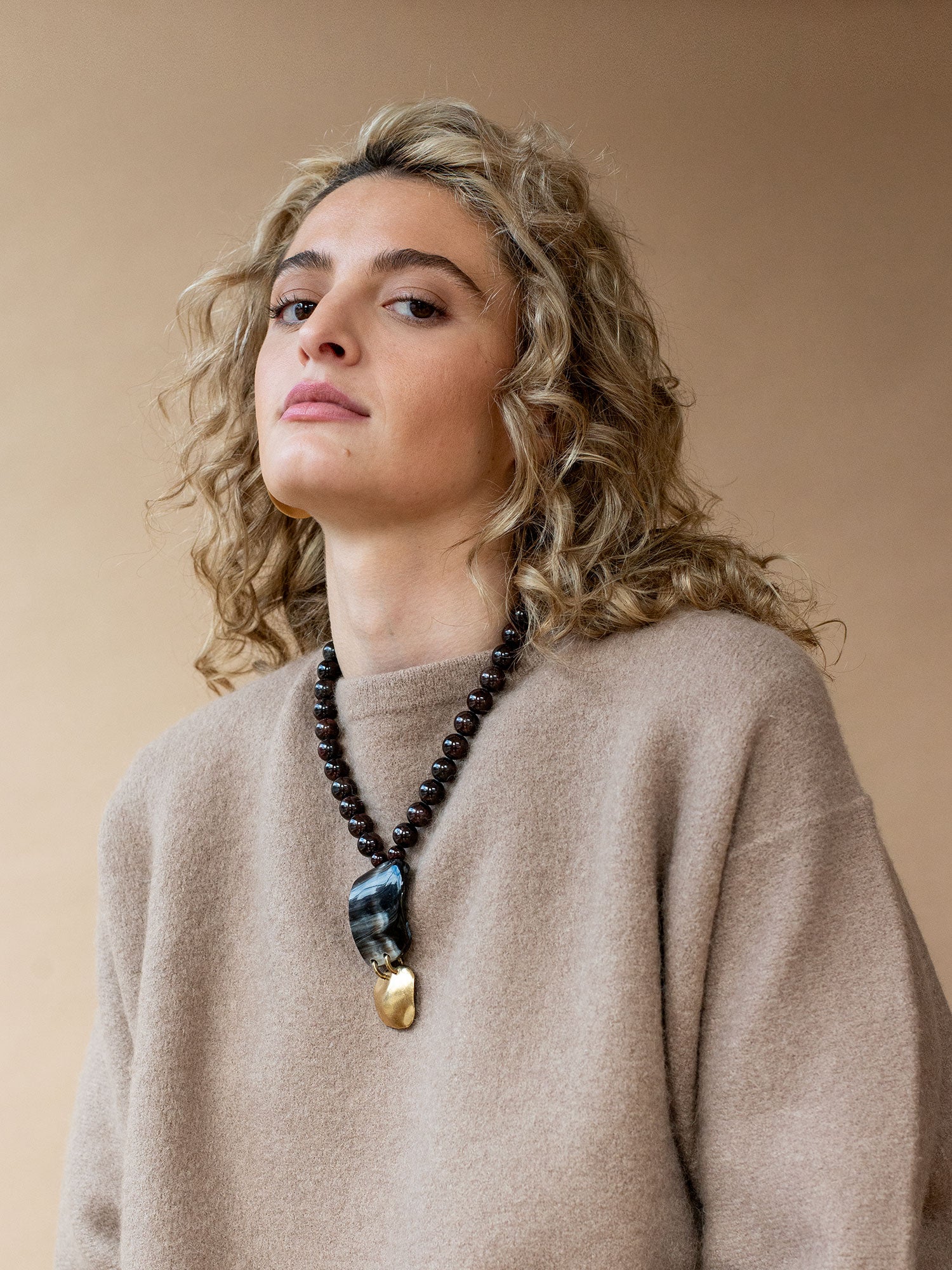 Necklace with garnet beads and a large black horn and brass pendant by Michelle Ross