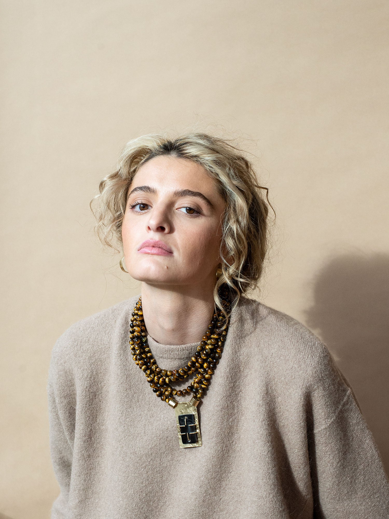 A multistrand beaded necklace with a central rectangular brass pendant with brown horn by Michelle Ross