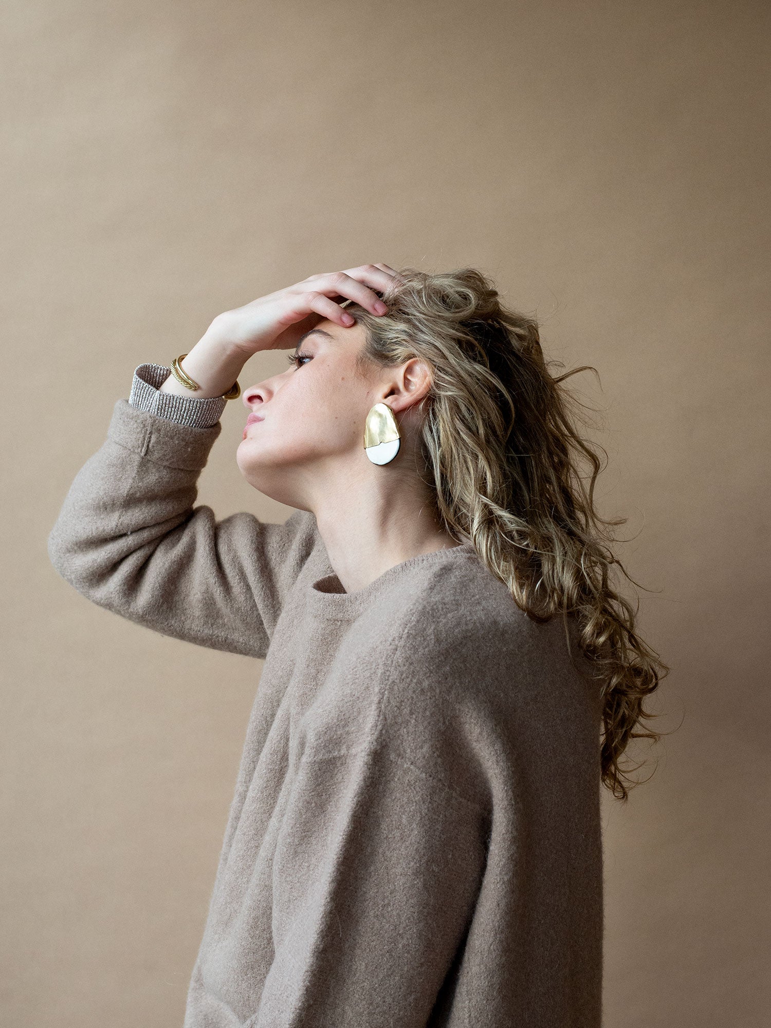 Pair of statement stud earrings with brass tops and blonde buffalo horn bases in a rounded shape by Michelle Ross