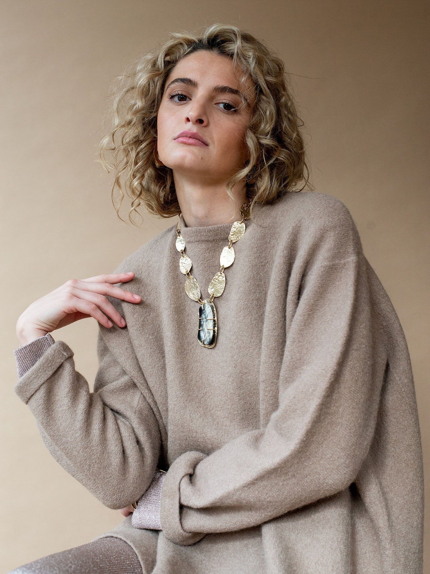 A brass statement necklace with hammered brass discs and a large central horn pendant by Michelle Ross 