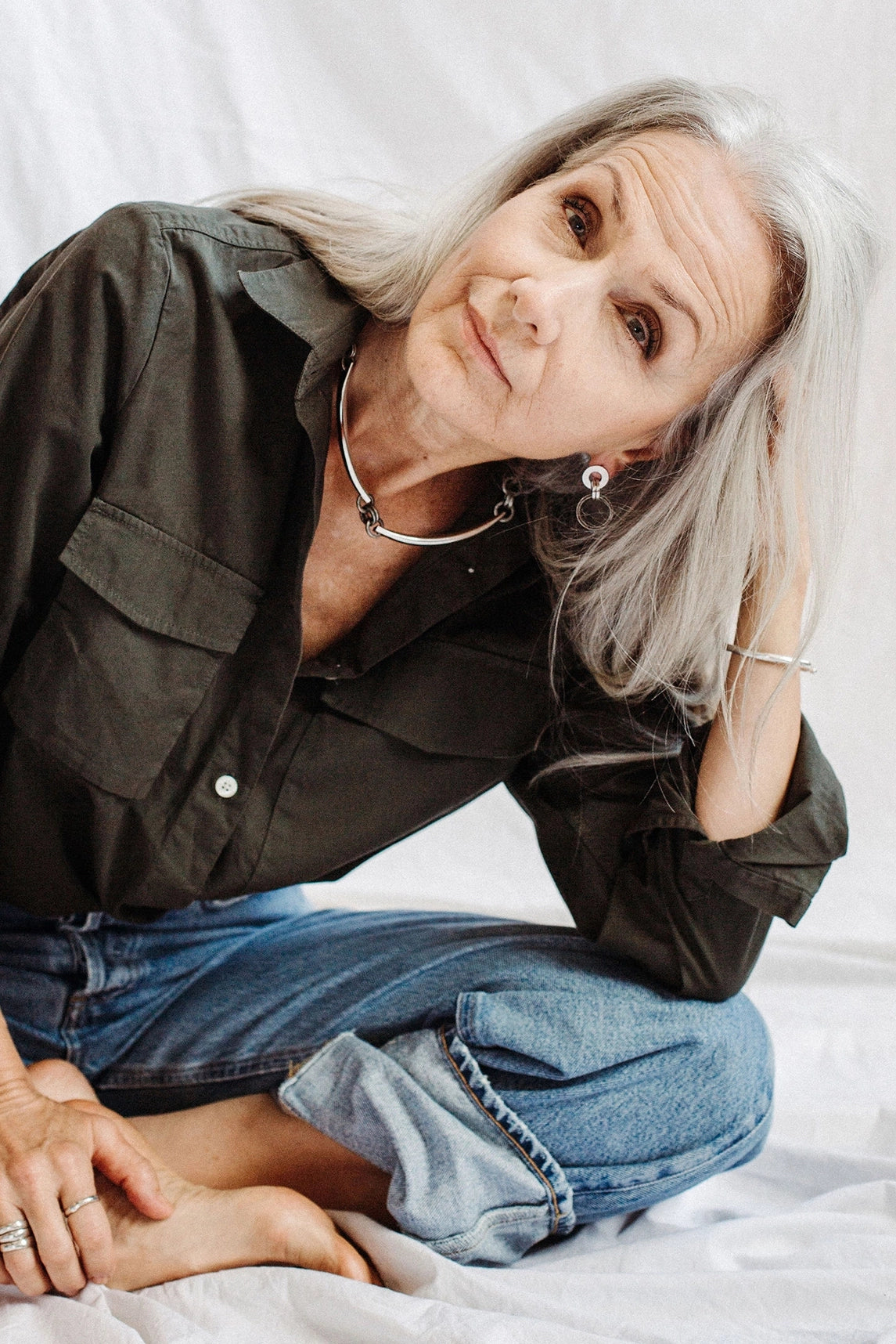 Woman with gray hairwearing sterling silver necklace, earrings, rings and bracelets by Canadian designer Michelle Ross