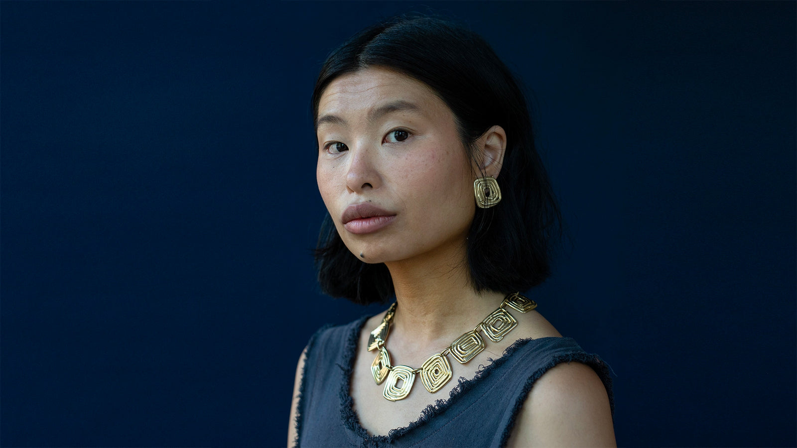 Woman wearing brass jewelry statement necklace and statement earrings by Toronto Designer Michelle Ross
