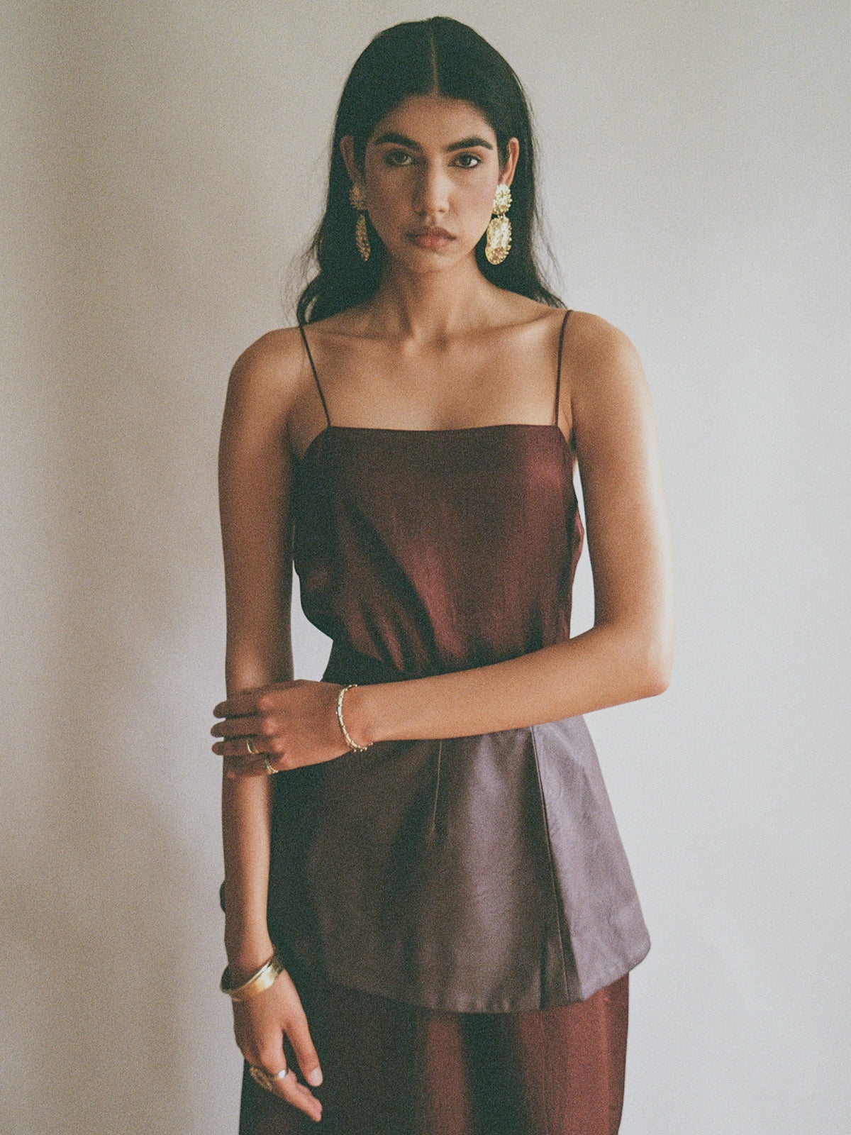 A woman wears brass jewelry handmade by Toronto designer Michelle Ross. She wears large statement earrings, solid bangle cuff bracelets and statement rings