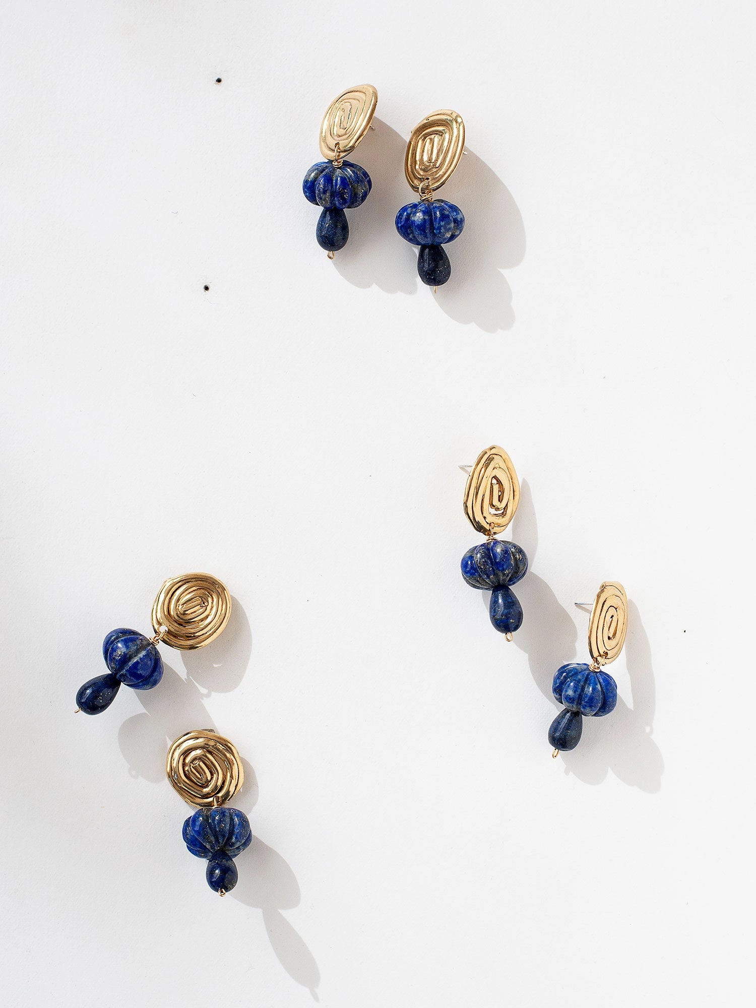 A pair of hand-formed brass spiral earrings with lapis lazuli beaded stone drop style by Canadian jewelry designer Michelle Ross