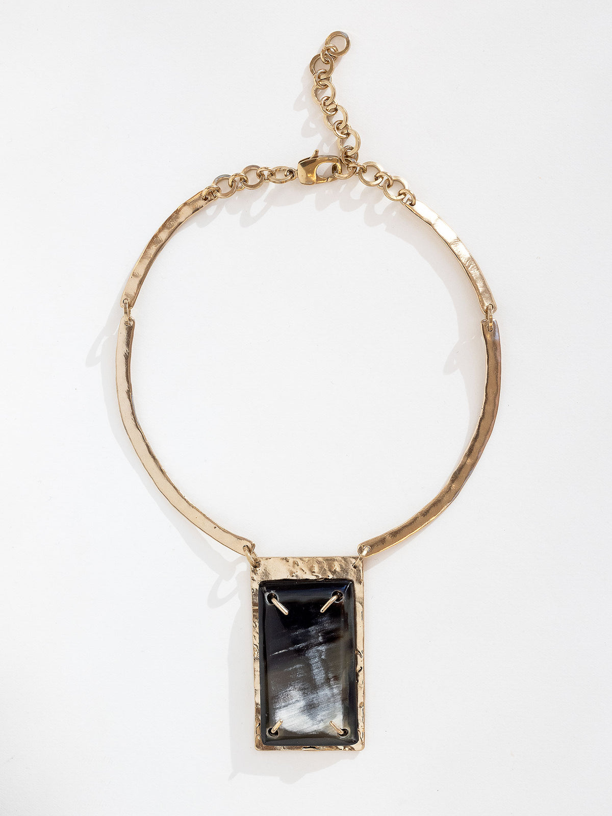 A solid brass collar necklace featuring a statement black horn pendant  by Michelle Ross