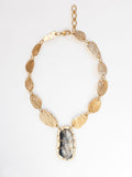 A brass statement necklace with hammered brass discs and a large central horn pendant by Michelle Ross 