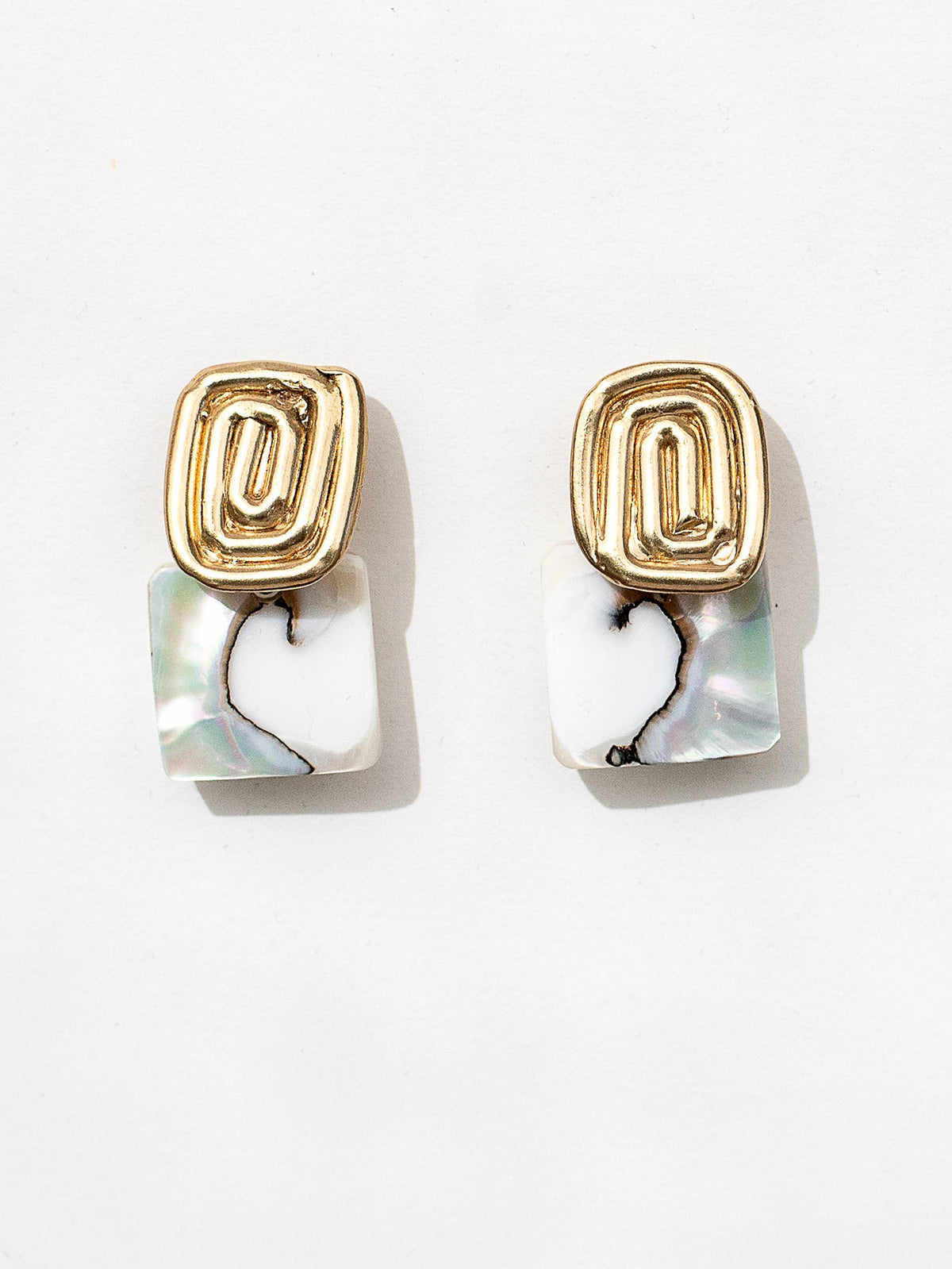 A pair of brass spiral design earrings with square shell drops by Canadian jewelry designer Michelle Ross 