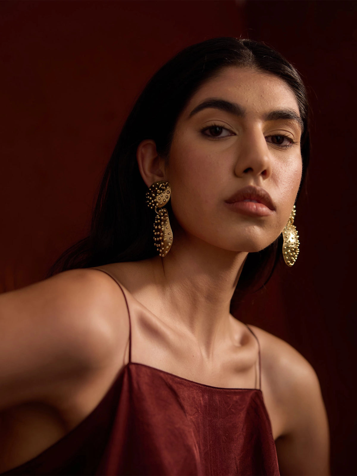 Woman wears Nisa Handmade Large Brass Statement Earrings by Michelle Ross