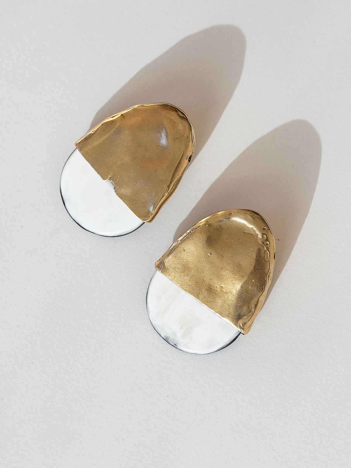 Pair of statement stud earrings with brass tops and blonde buffalo horn bases in a rounded shape by Michelle Ross
