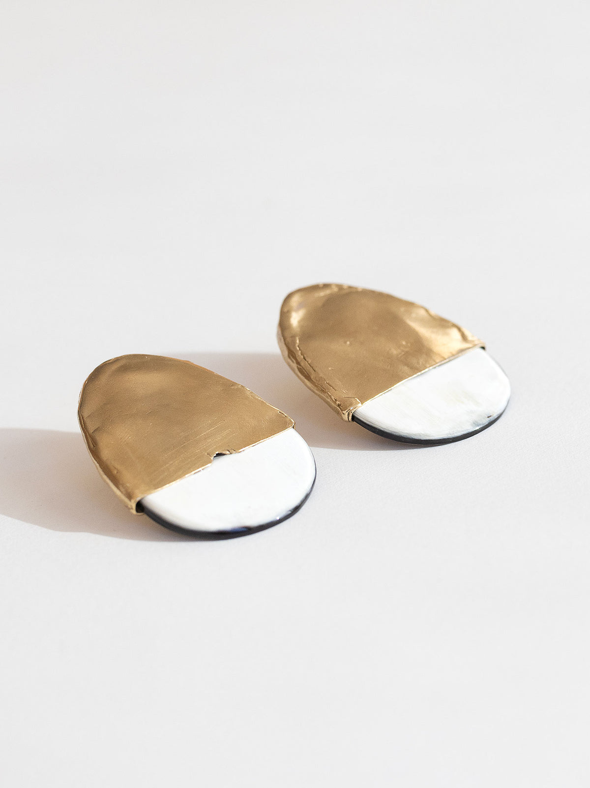 Pair of statement stud earrings with brass tops and blonde buffalo horn bases in a rounded shape by Michelle Ross