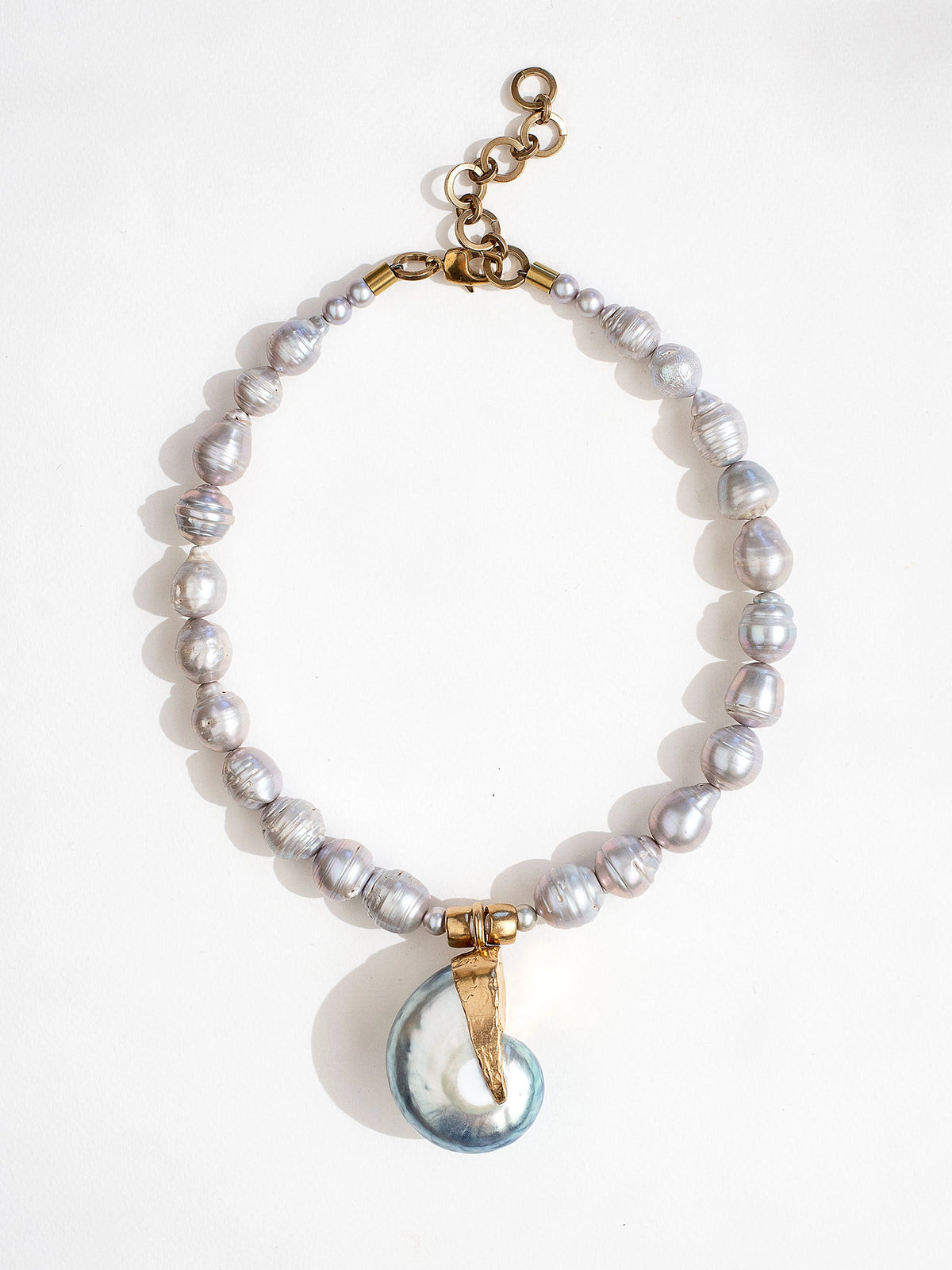 A baroque pearl beaded necklace with a large seashell and brass pendant by Canadian jewelry designer Michelle Ross