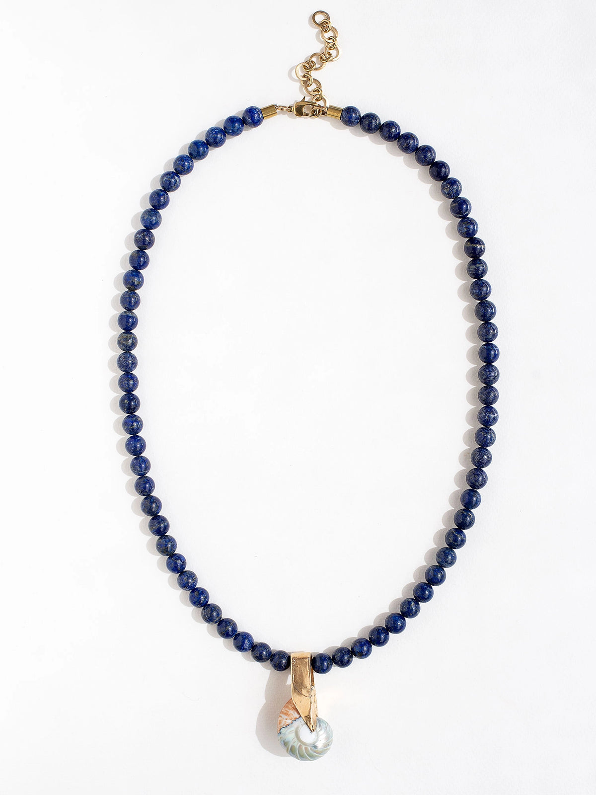 A lapis lazuli beaded necklace with large seashell and brass pendant by Canadian jewelry designer Michelle Ross