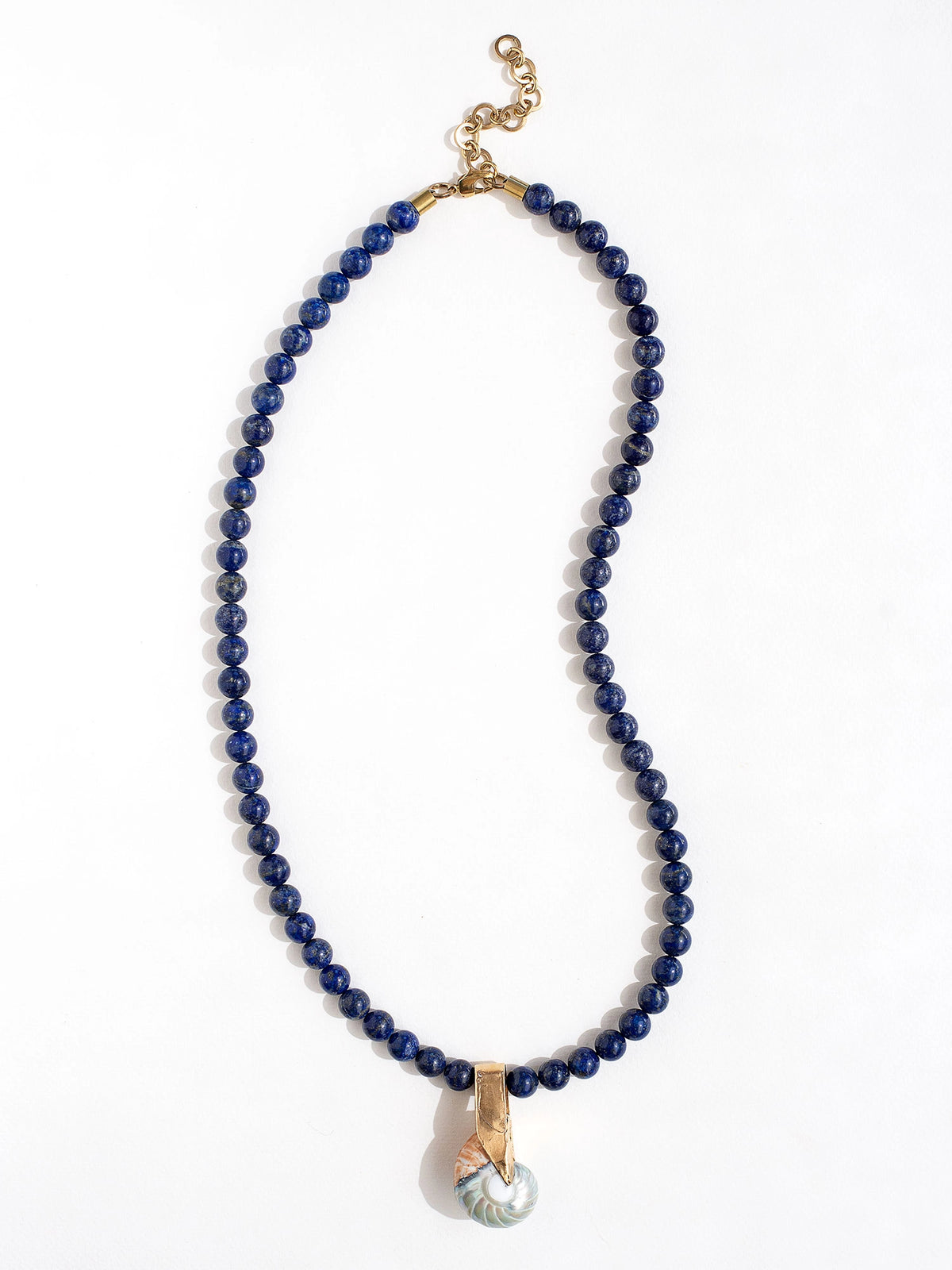 A lapis lazuli beaded necklace with large seashell and brass pendant by Canadian jewelry designer Michelle Ross