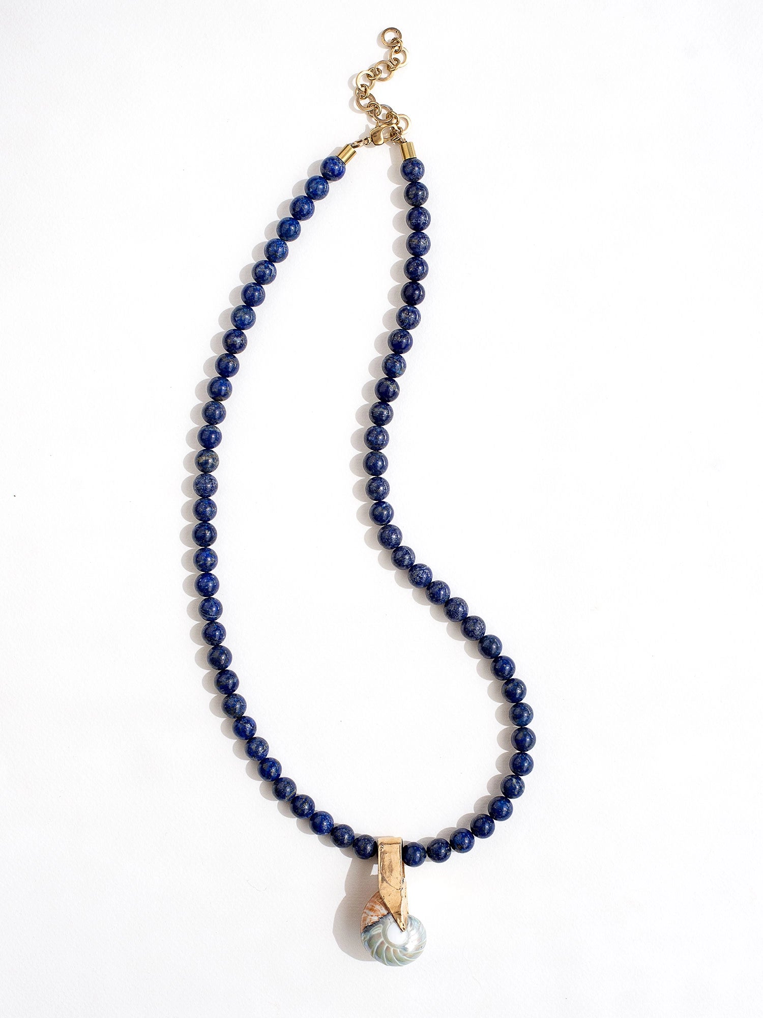 A lapis lazuli beaded necklace with large seashell and brass pendant by Canadian jewelry designer Michelle Ross