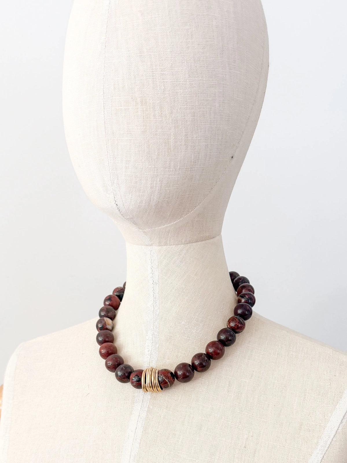 A beaded necklace made from red jasper stone beads with hand formed brass details by Canadian Jewelry Designer Michelle Ross