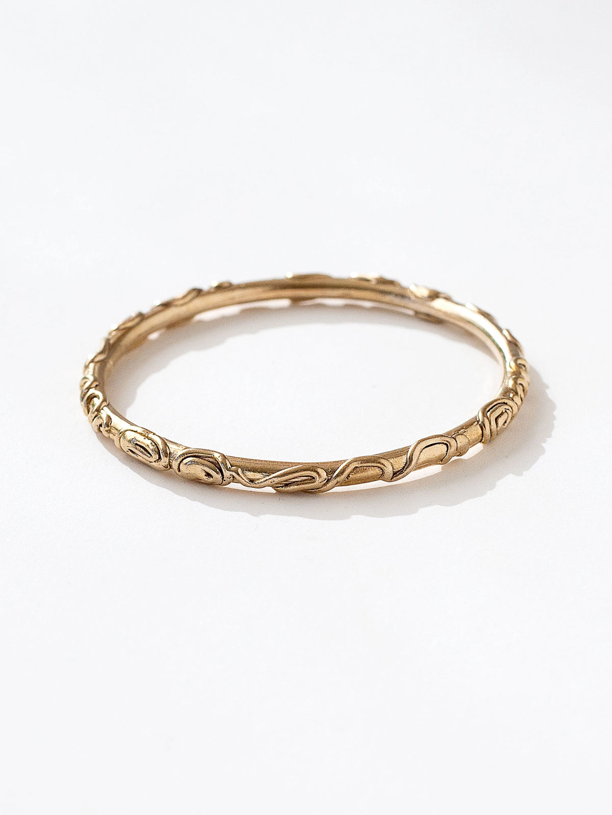 A solid brass bangle bracelet with spiral scrollwork details by Canadian jewelry designer Michelle Ross
