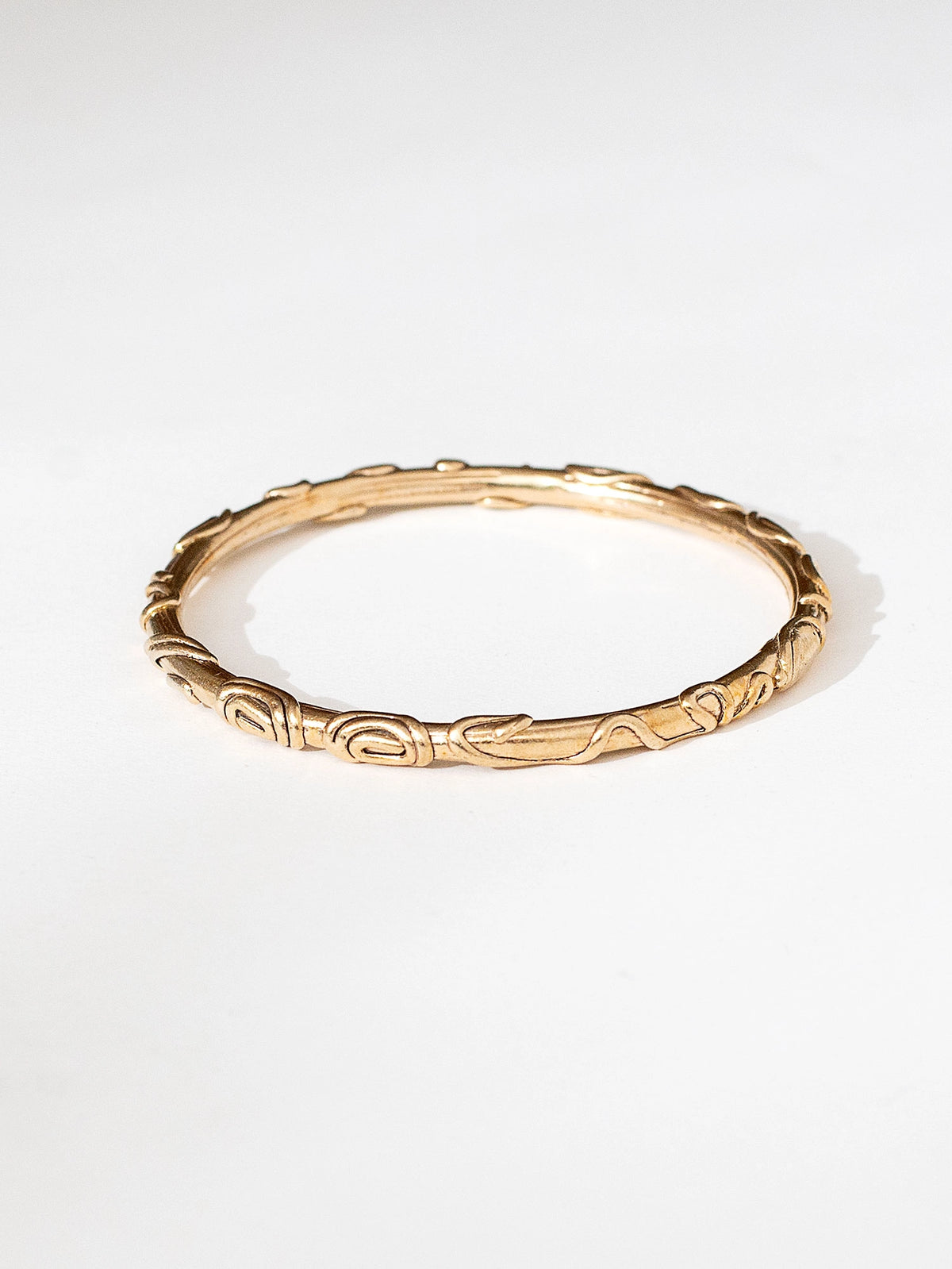A solid brass bangle bracelet with spiral scrollwork details by Canadian jewelry designer Michelle Ross