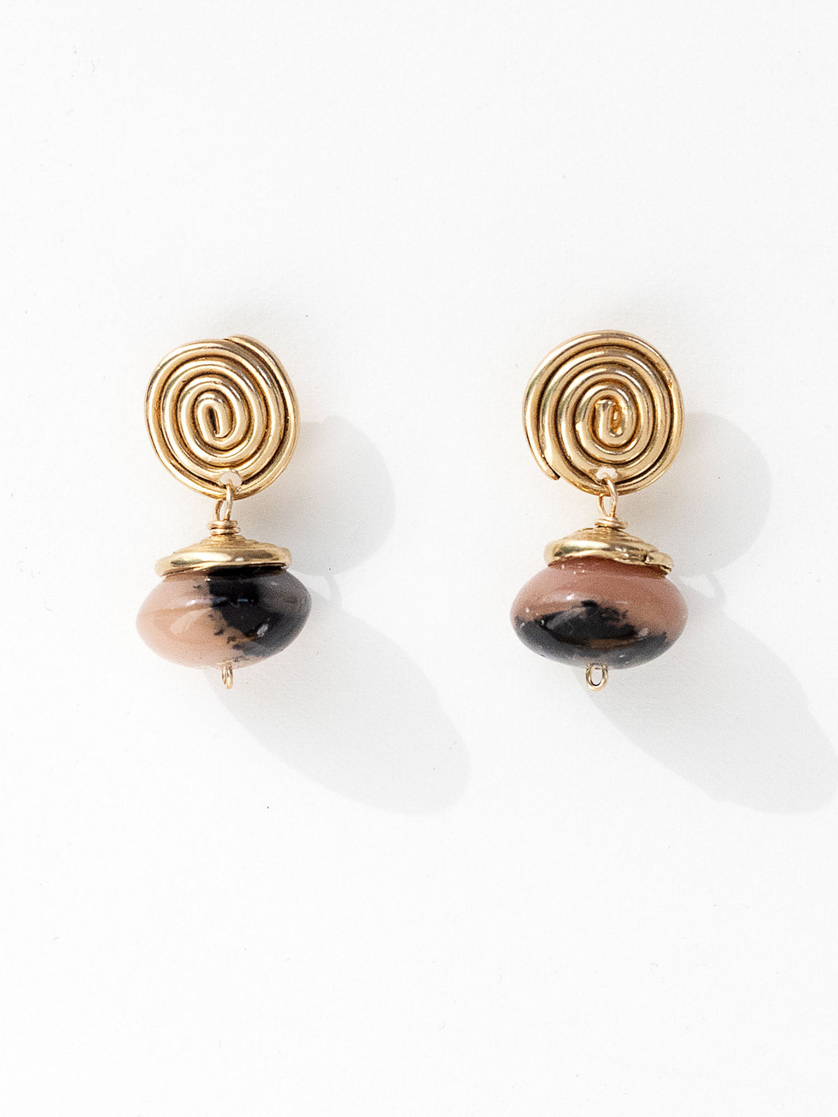 A pair of brass spiral drop earrings with marbled pink and black beads hanging below by Canadian jewelry designer Michelle Ross