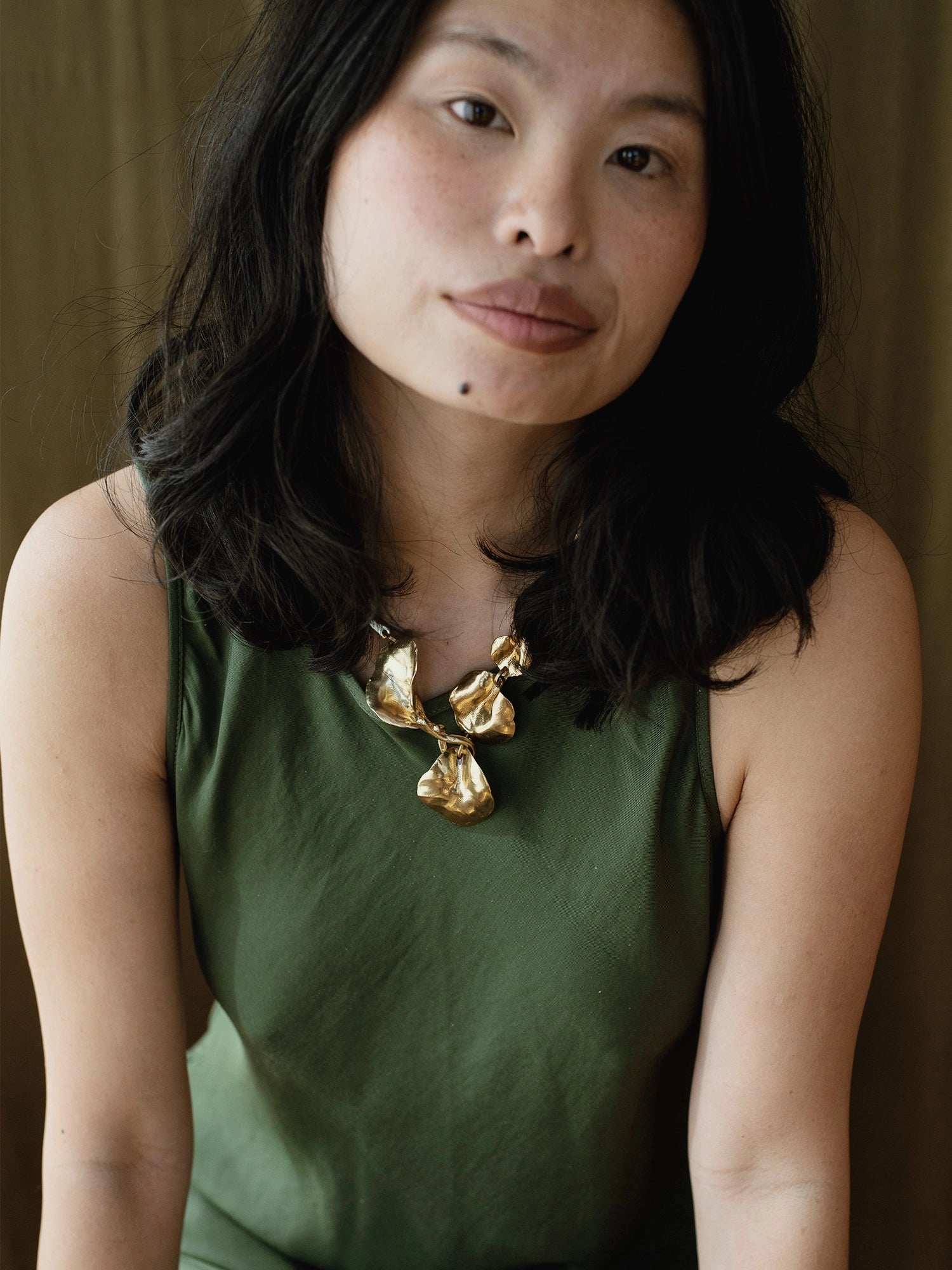 a woman wears a brass statement collar necklace with abstract floral sculptural designs by Canadian designer Michelle Ross