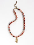A beaded necklace featuring light pink stone with grey marbled beads, dark red beads, accented with a brass metal clasp by Canadian jewelry designer Michelle Ross