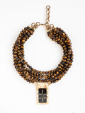 A multistrand beaded necklace with a central rectangular brass pendant with brown horn by Michelle Ross