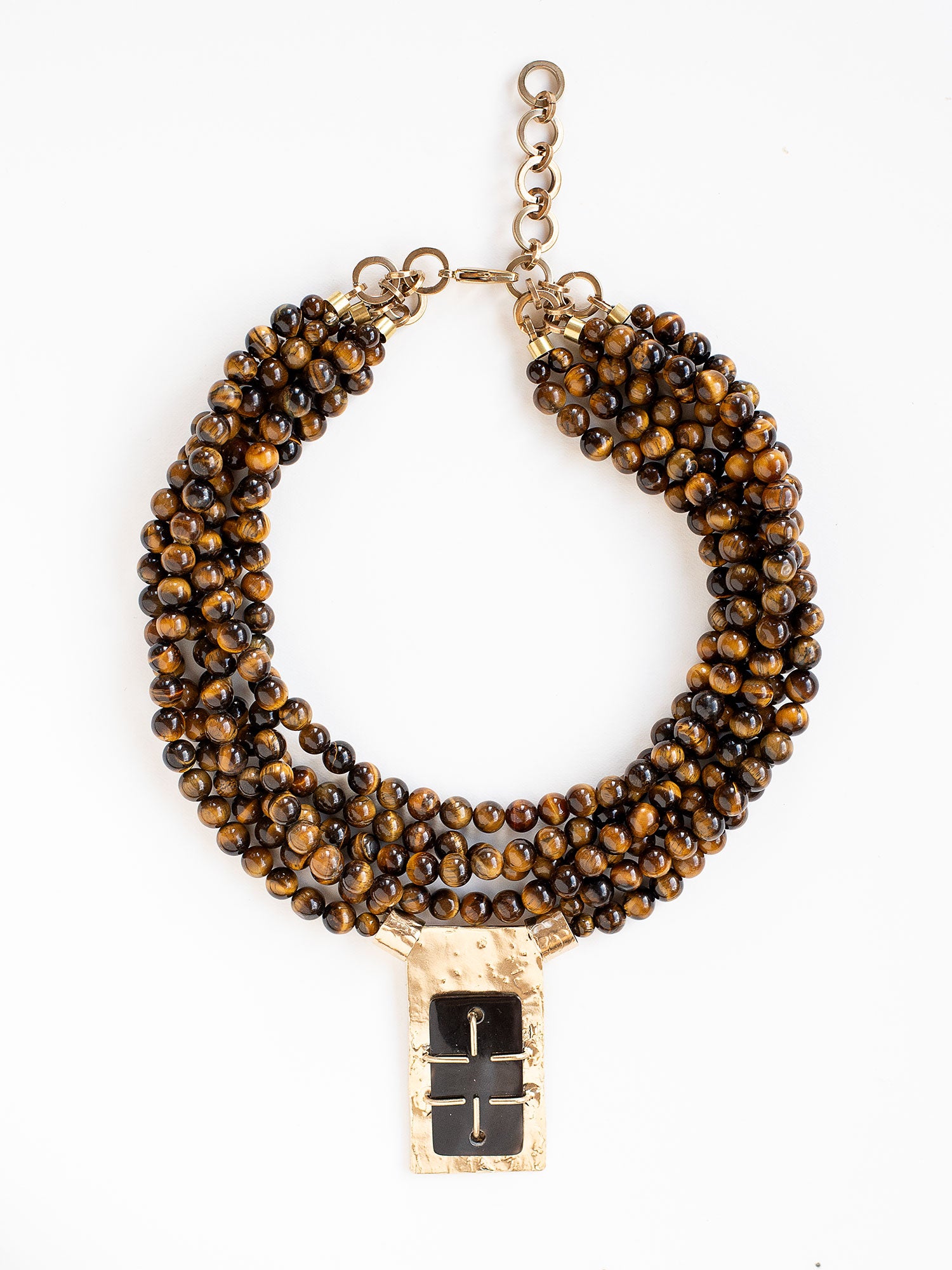 A multistrand beaded necklace with a central rectangular brass pendant with brown horn by Michelle Ross