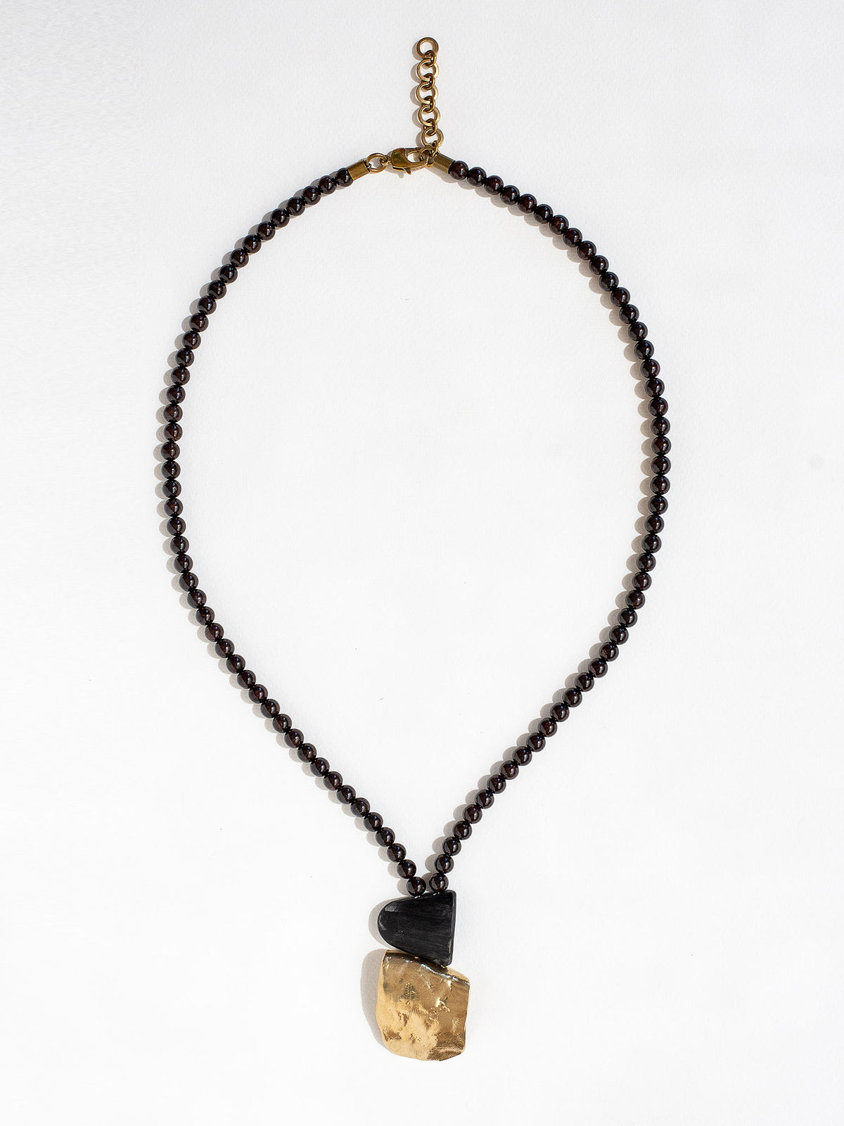 Necklace with garnet beads and a brass pendant by Canadian designer Michelle Ross