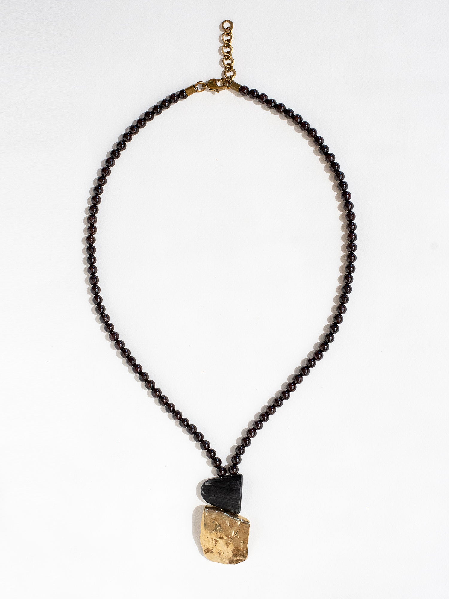Necklace with garnet beads and a brass pendant by Canadian designer Michelle Ross