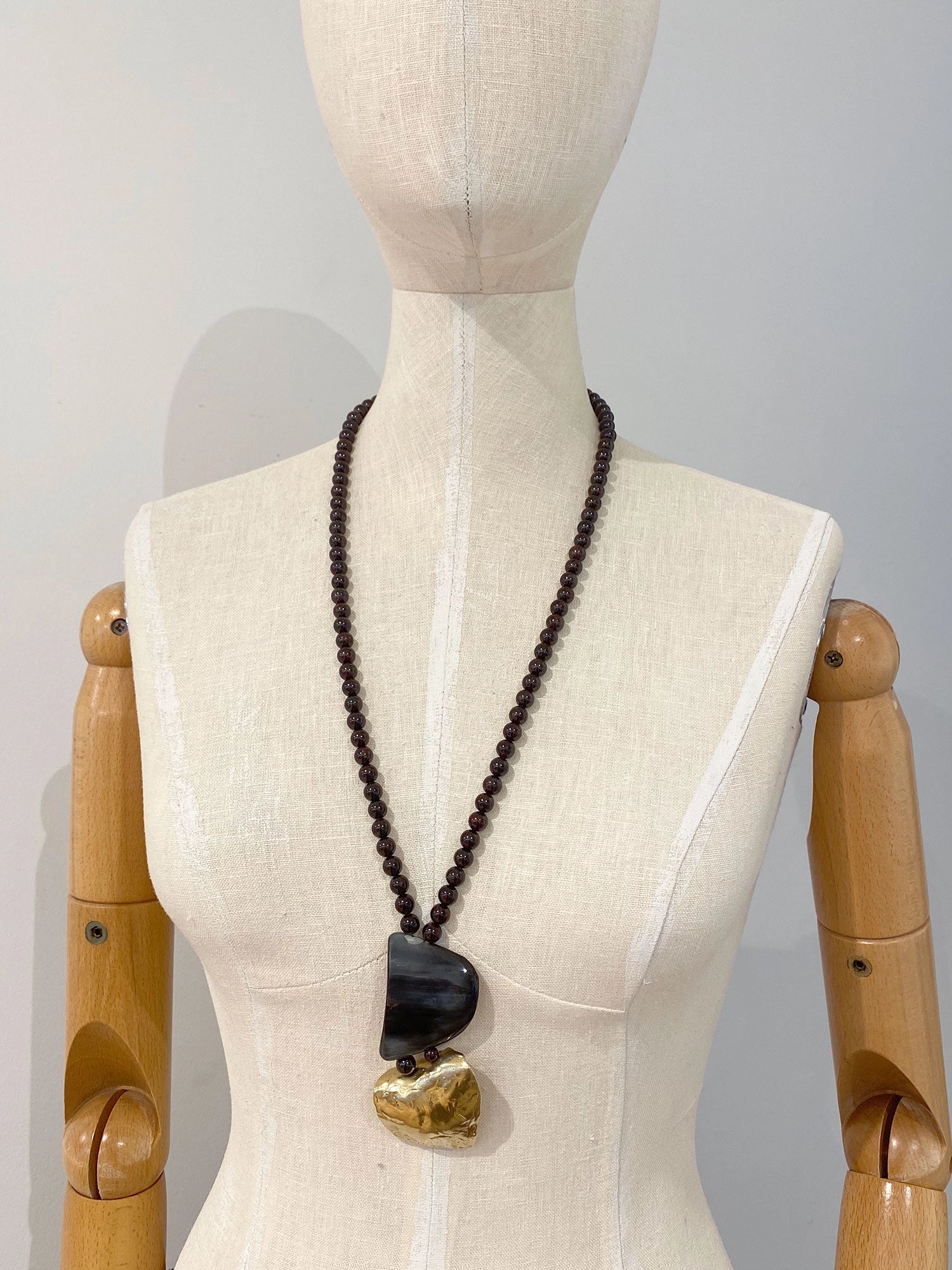 Necklace with garnet beads and a large horn and brass pendant  by Michelle Ross