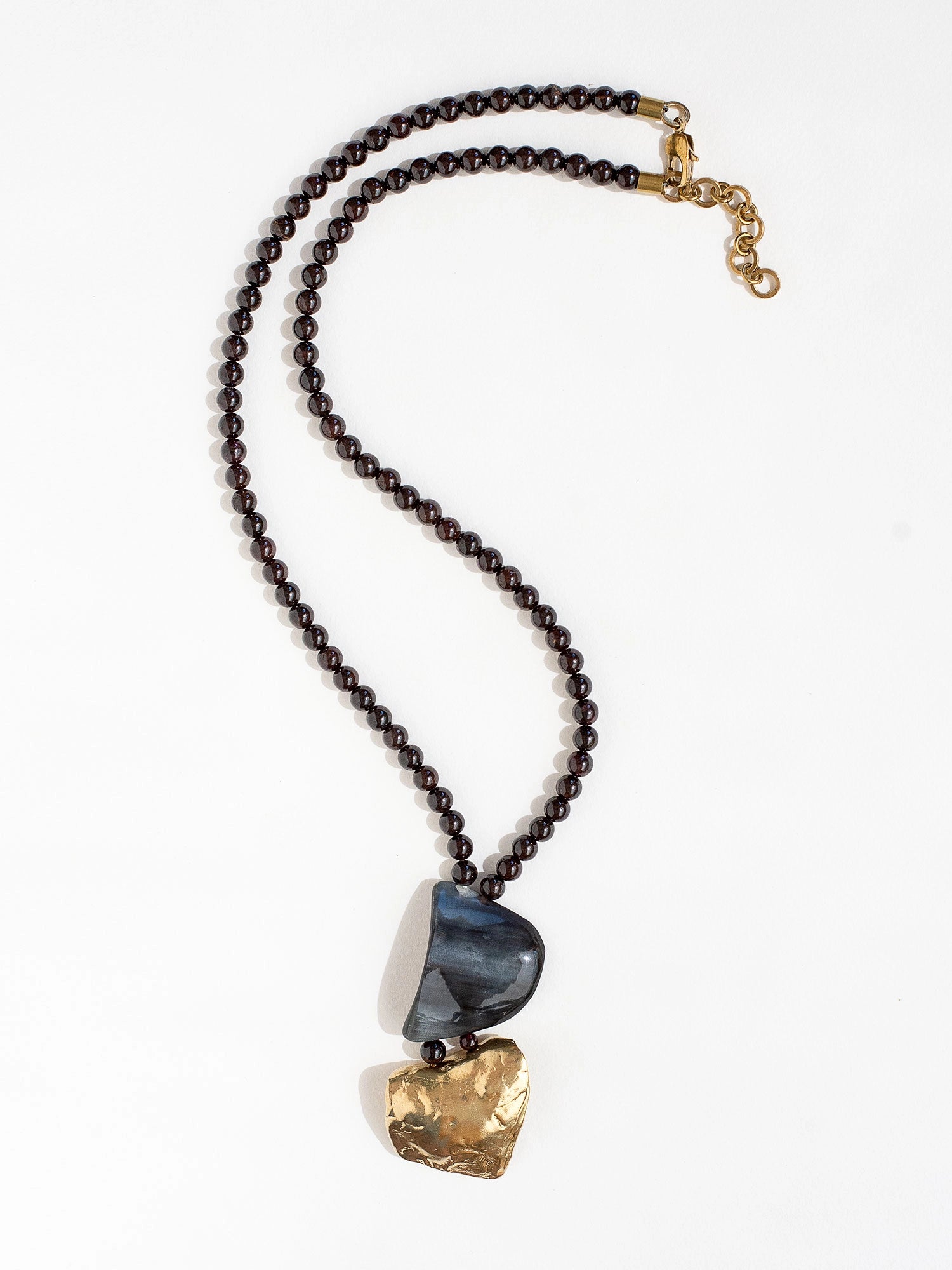 Necklace with garnet beads and a large horn and brass pendant  by Michelle Ross