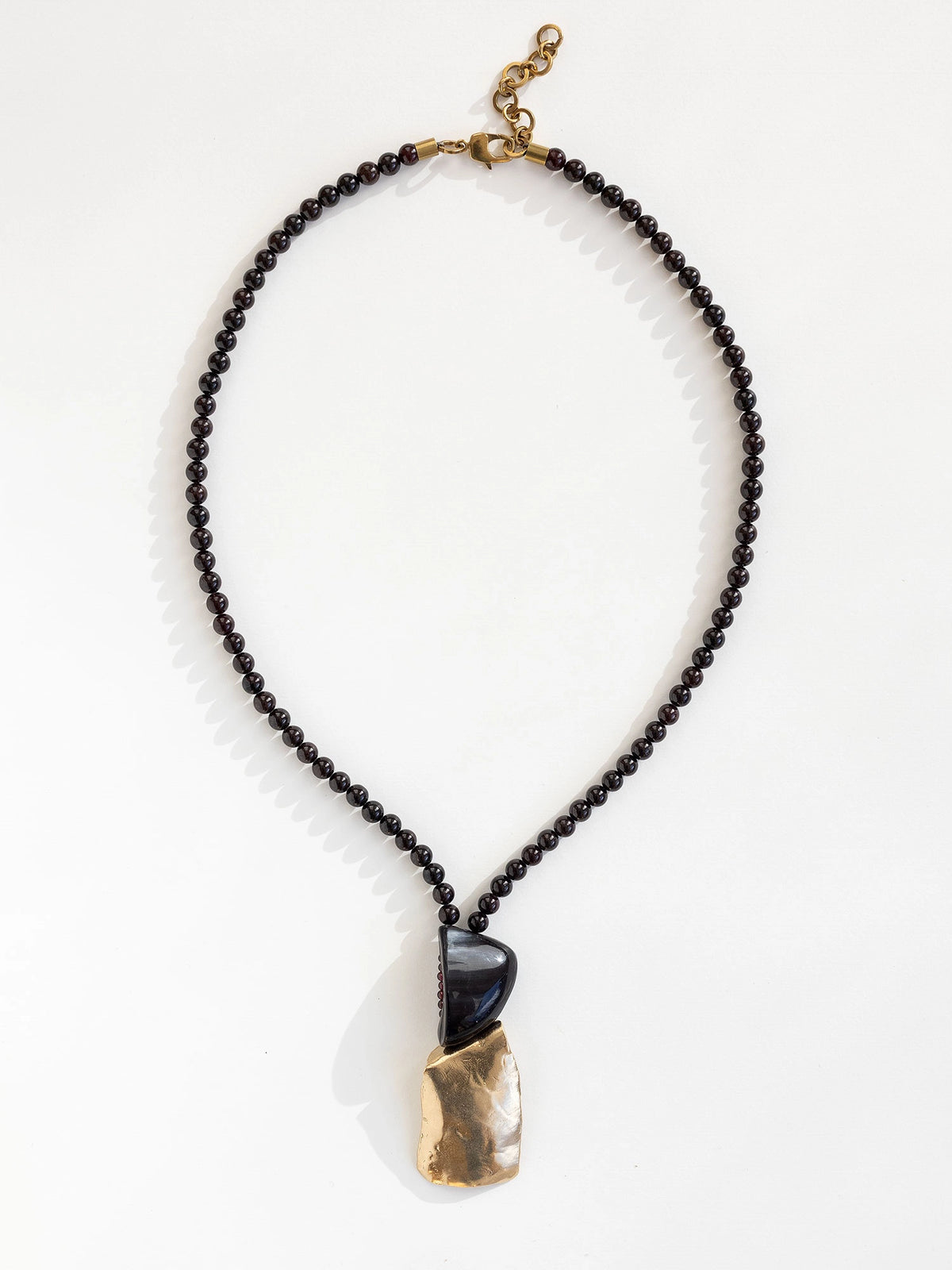 Necklace with garnet beads and a horn and brass pendant by Canadian designer Michelle Ross
