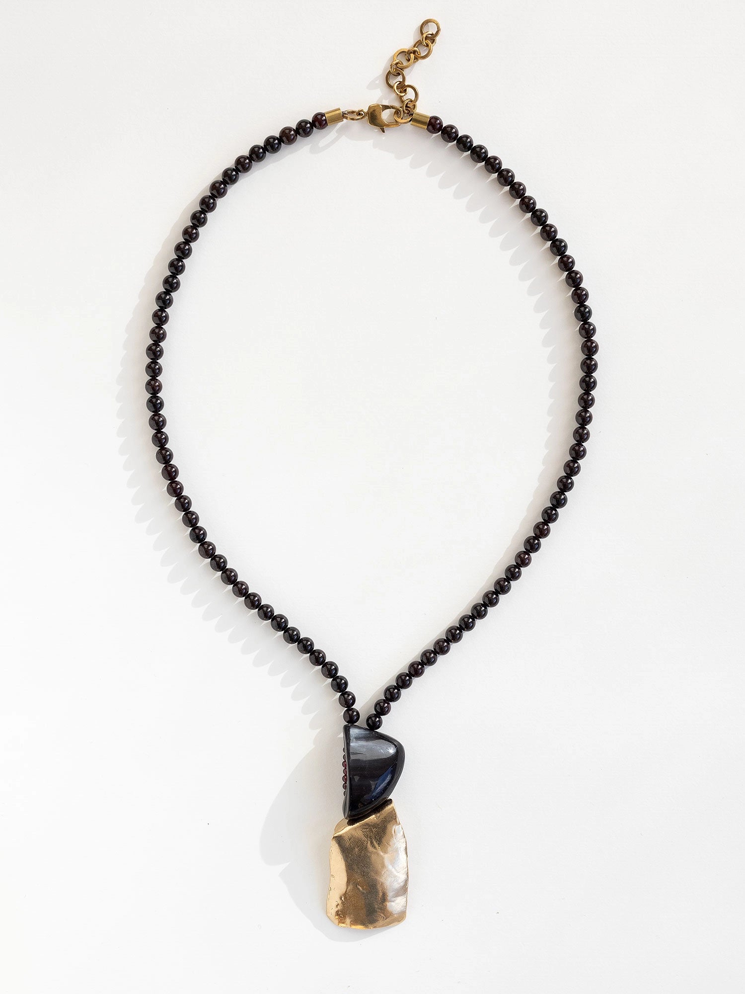 Necklace with garnet beads and a horn and brass pendant by Canadian designer Michelle Ross