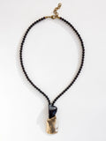 Necklace with garnet beads and a horn and brass pendant by Canadian designer Michelle Ross