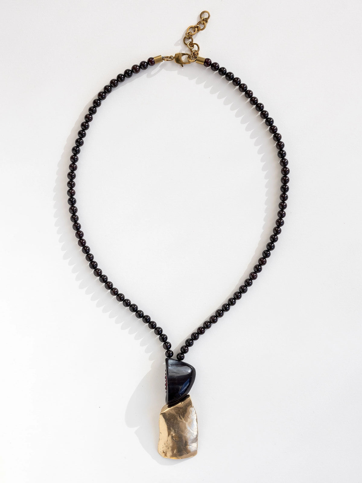 Necklace with garnet beads and a horn and brass pendant by Canadian designer Michelle Ross