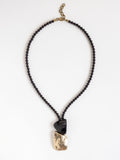 Necklace with garnet beads and a horn and brass pendant by Canadian designer Michelle Ross