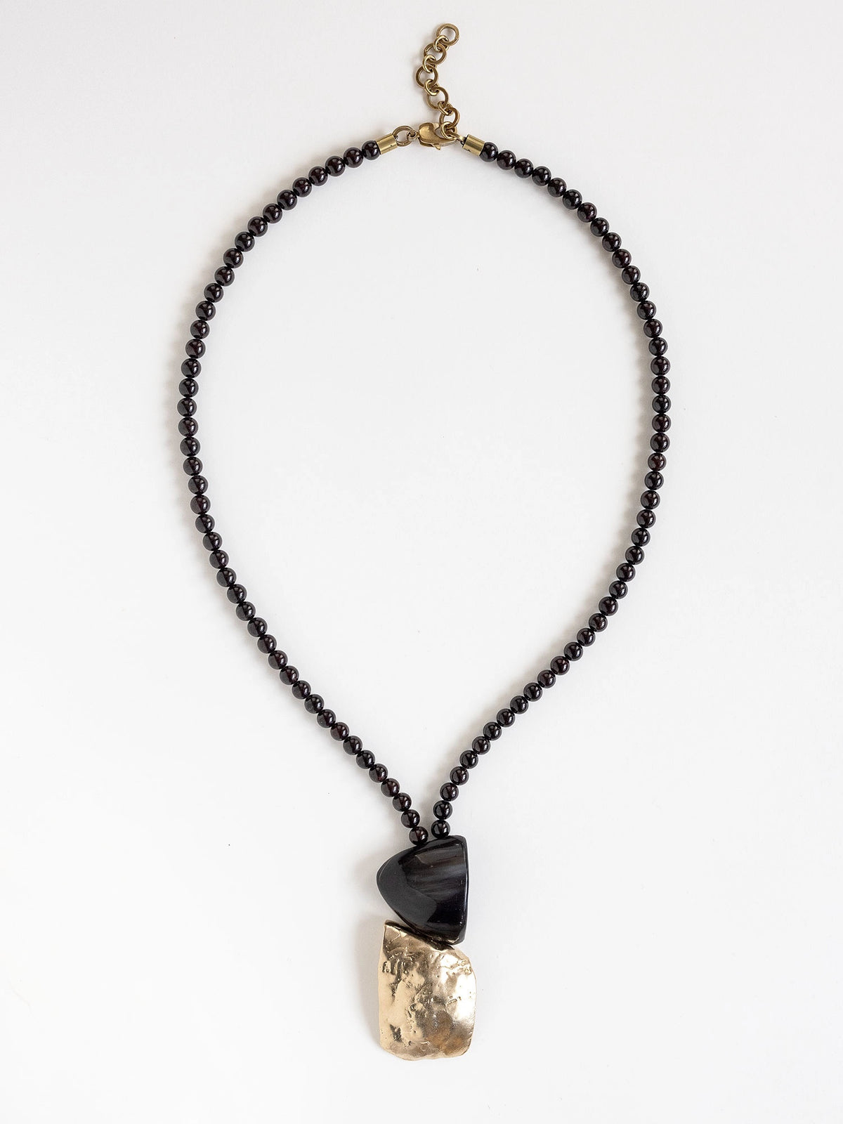 Necklace with garnet beads and a horn and brass pendant by Canadian designer Michelle Ross