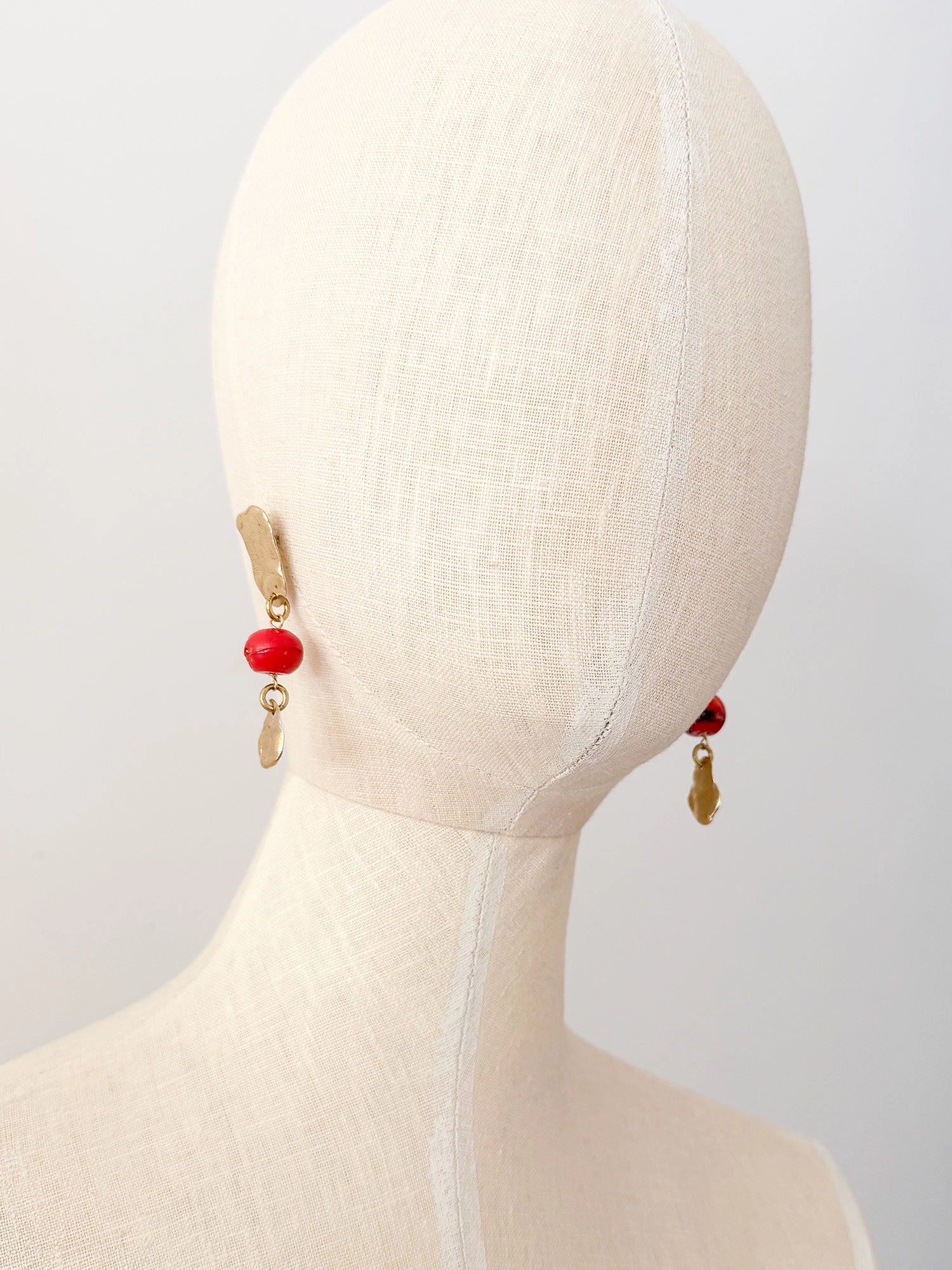 A pair of handmade dangle brass earrings red coral and a small hand formed brass bead by Canadian jewelry designer Michelle Ross.