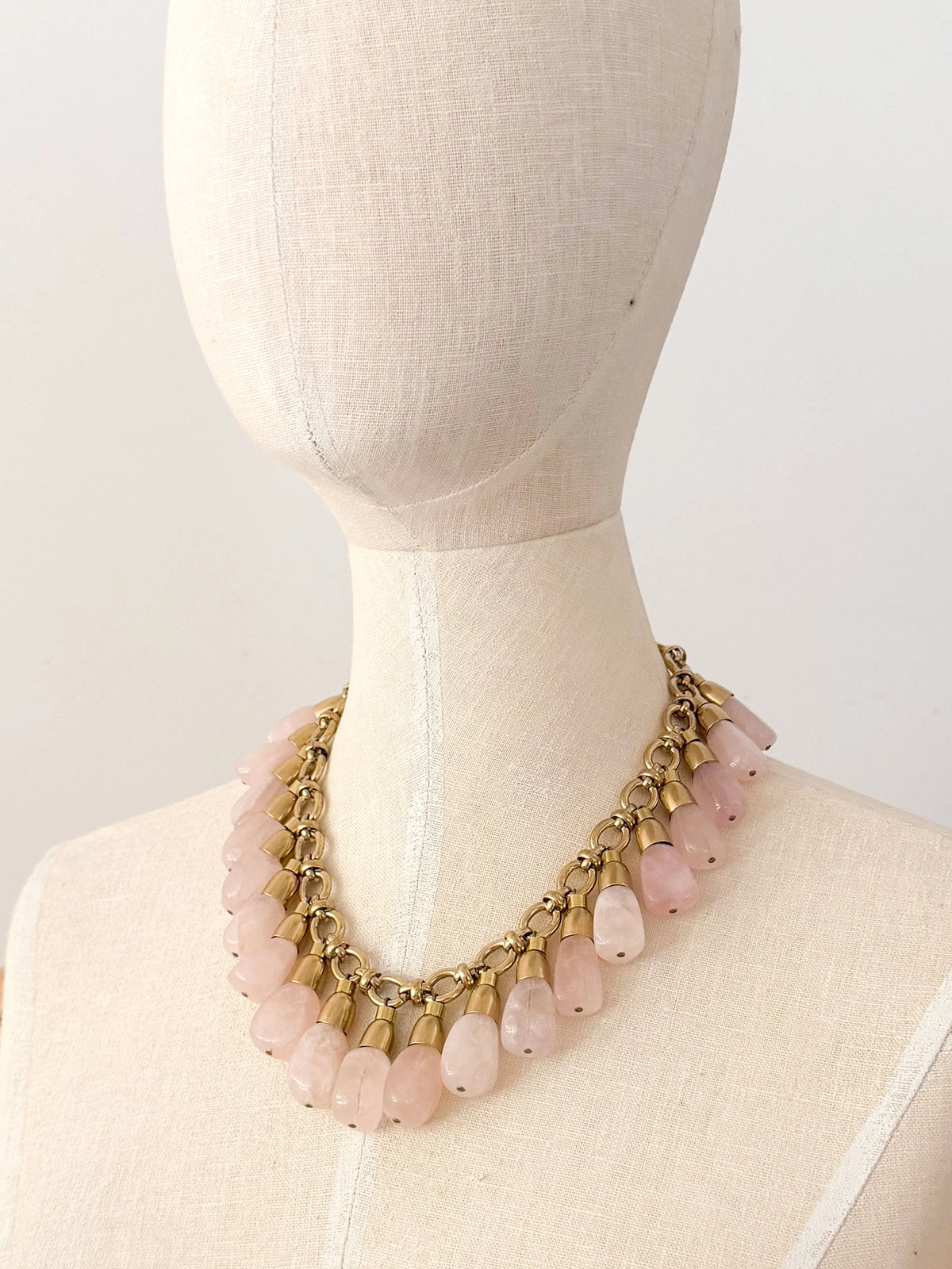 A statement collar necklace featuring a brass chain and links with large dangling rose quartz beads by Canadian designer Michelle Ross